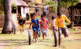 Fröhliche Kinder mit dunkler Hautfarbe spielen mit rollenden Reifen