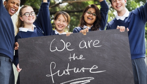 Fünf Jugendliche in Schuluniform halten ein Schild mit der Aufschrift We are the future